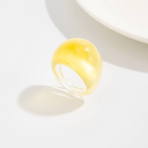 Nahaufnahme eines gelben, transparenten Harzrings im Retro-Design auf weißem Grund