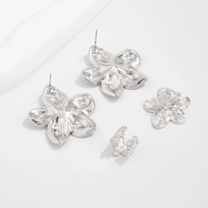Detail eines silbernen Blumenschmuck-Sets mit gehämmerten Ohrringen und Ear Cuffs