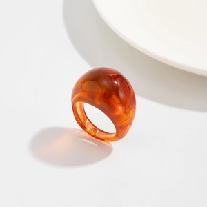 Makroaufnahme von klobigem Bernstein-Resin-Ring mit Vintage-Schildpatt-Textur auf weißer Keramik