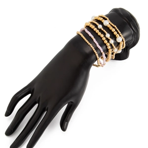 Gros plan sur un ensemble de bracelets perlés avec perles dorées et pendentif croix en coquillage