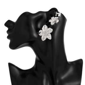 Detailansicht von drei silbernen Blumen-Ohrklemmen in absteigender Größe an einem Modell