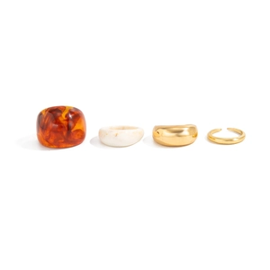 Detail view of 4-piece ring set featuring amber resin and polished gold metal bands