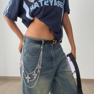 Detail of layered silver cross chains on denim jeans for street punk Y2K fashion style