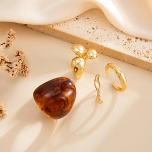 Detailopname van een barnsteenkleurige ring en gepolijste gouden banden op zijde