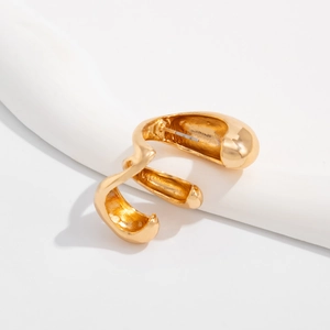 Close-up of golden minimalist C-shaped geometric hoop earring with a polished wavy surface