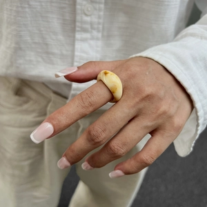 Detailansicht eines dicken bernsteinfarbenen Harzrings mit Marmortextur am Finger