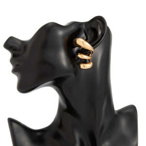 Macro detail of triple spiral golden hoop earrings with polished mirror finish on a black display