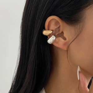 Detail of gold and silver polished C-shaped ear cuffs layered on ear model