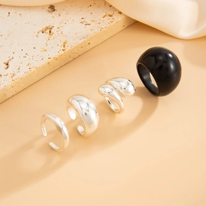 Set van gepolijste zilveren ringen en zwarte ring op luxe stenen display-standaard
