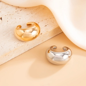 Detailed view of thick C-shaped gold and silver earrings with high-polish mirror finish