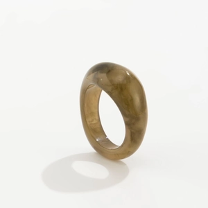 Detail eines klobigen olivbraunen Marmorharzrings mit lichtdurchlässigem Glanz