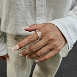 Nahaufnahme eines minimalistischen, transparenten Harzrings an einem Zeigefinger