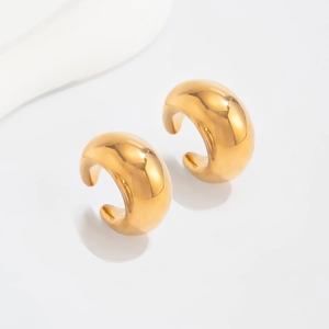 Macro shot of chunky gold C-shaped hoop earrings with polished geometric finish