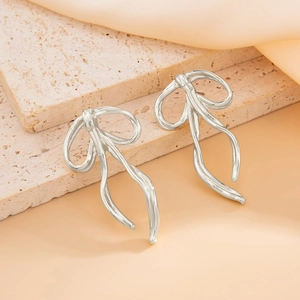 Detailed view of silver bow-shaped metallic earrings resting on a textured stone