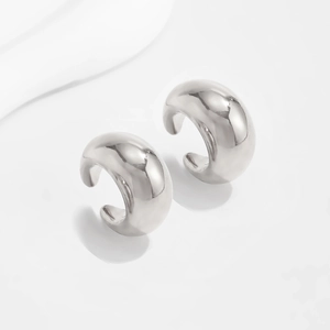 Macro detail of polished silver C-shape ear cuff with a glossy mirror-like metallic finish
