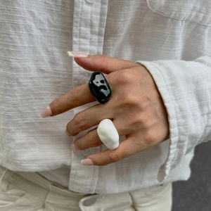 Nahaufnahme minimalistischer schwarz-weißer Harzringe an der Hand eines Models