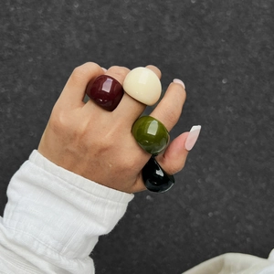 Primo piano di un set di 4 anelli spessi in resina nei colori bordeaux e oliva
