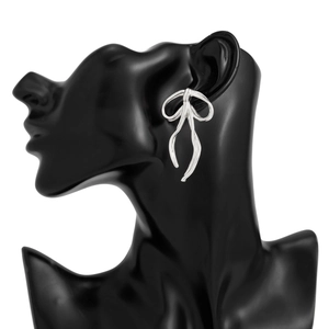 Detail of silver bow earrings with smooth metallic finish on a black display model