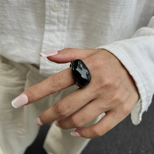 Detail eines klobigen schwarzen Harzrings mit unregelmäßigem organischem Lava-Design