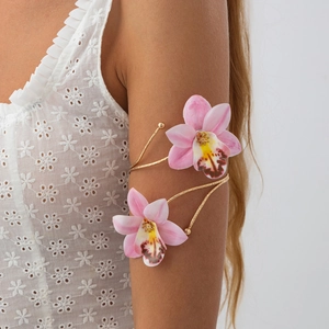 Boho gouden bovenarmband met realistische roze orchideeënbloemen bij een model
