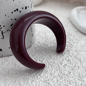 Dettaglio del bracciale aperto in resina rosso scuro con finitura a specchio lucida