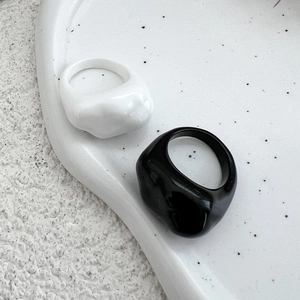 Minimalistische dicke Harzringe in Schwarz und Weiß auf weißem Keramik-Tablett