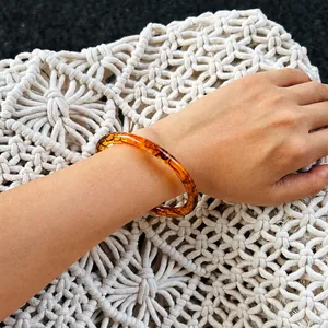 Primo piano di un bracciale in resina ambrata con texture tartarugata su fondo intrecciato