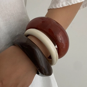 Retro irregular resin bangle set in coffee, cream, and amber colors on model wrist