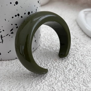 Vista macro di un bracciale aperto in resina verde scuro lucido su base