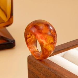 Makroansicht breiter bernsteinfarbener Harzring mit Marmortextur auf Holzdisplay