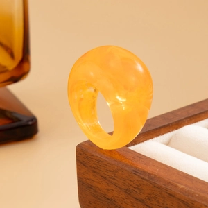 Nahaufnahme eines lichtdurchlässigen orangefarbenen Harzrings mit Marmortextur
