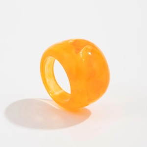 Detail eines durchscheinenden orangefarbenen Harzrings mit klobigem glänzendem Design