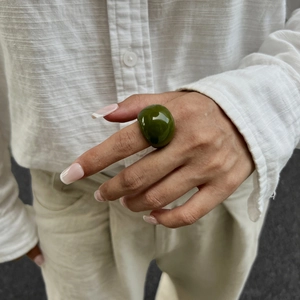 Dettaglio di un anello voluminoso in resina verde oliva sulla mano di una modella