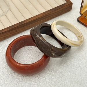 Close-up of thick resin bangles with amber, coffee, and ivory marble textures