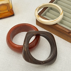 Three-piece irregular acrylic resin bangle set with marble texture on wooden stand
