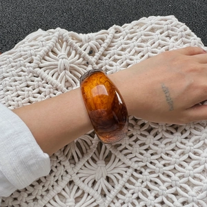 Dettaglio macro del bracciale in resina ambrata con trama liscia e motivo tartarugato