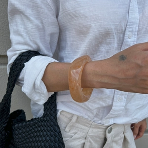 Detailed view of an amber marble resin chunky bangle with translucent finish on a wrist