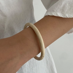 Detailed close-up of smooth ivory resin bangle showing refined matte texture and minimalist design