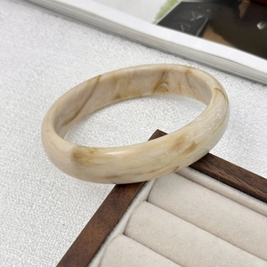 Dettaglio di un bracciale minimalista in resina marmorizzata con trama in pietra ambra