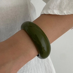 Macro detail of glossy dark green resin bangle with smooth polished surface on wrist