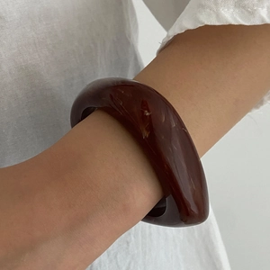 Close-up of a wide amber acrylic resin cuff bracelet with marble texture on wrist