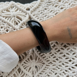 Close-up of a chunky dark tortoise resin bangle with a polished mirror finish