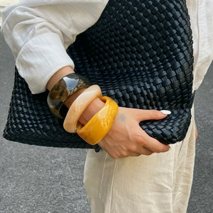 Primo piano di tre larghi bracciali in resina tartarugata e beige sul polso