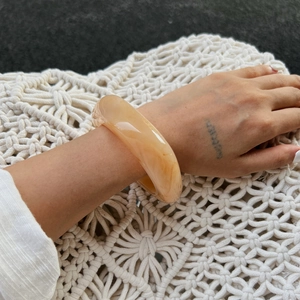 Dettaglio di un bracciale largo in resina marmorizzata con texture sfumate marroni e beige