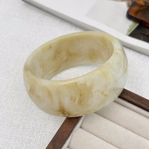 Detailansicht eines marmorierten Harz-Armreifs mit weicher cremefarbener und brauner Textur
