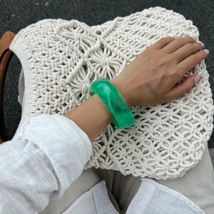 Close-up of translucent green resin bangle with marble texture on model hand