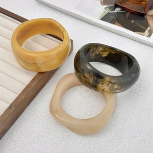 Dettaglio del set di bracciali larghi in resina color ambra e tartaruga su vassoio
