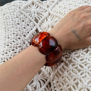 Macro view of polished amber acrylic chunky bracelet on wrist with marbled resin texture