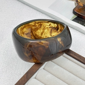 Détail d'un bracelet en résine ambre avec motif écaille sur plateau en bois