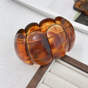Detailed view of amber resin acrylic bangle with translucent tortoiseshell texture